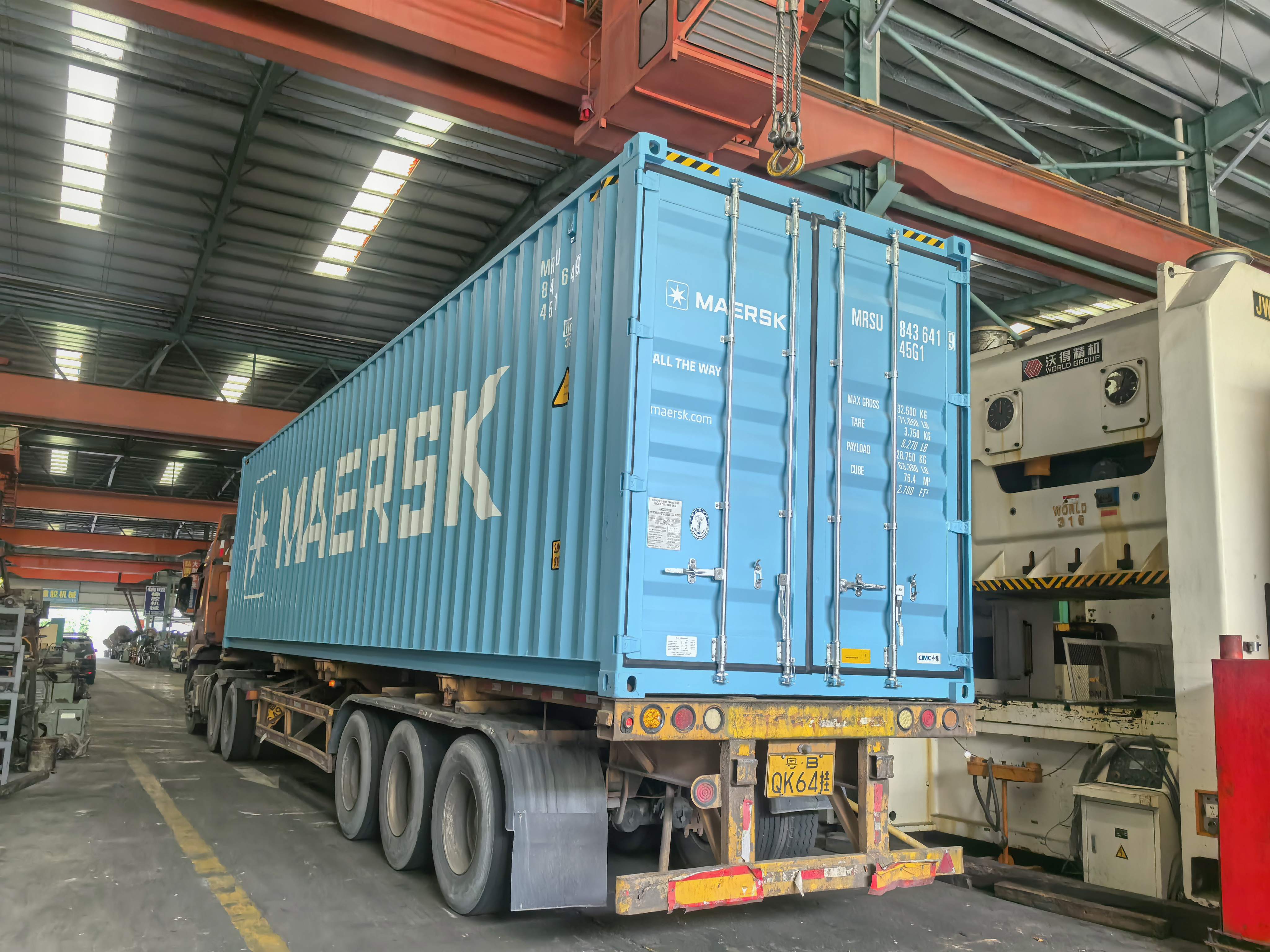 Loading press machine into containers, shipping to South Asia